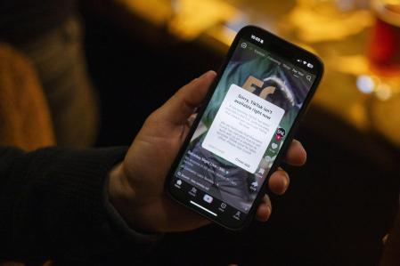 Una persona sostiene un teléfono inteligente con un mensaje en su aplicación TikTok que no está disponible en Washington, DC, EE.UU.