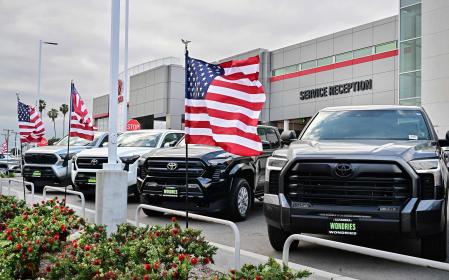 US flags fly outside a Toyota dealership in Alhambra, California, on March 27, 2025. Automakers were battered on March 27 as stock markets fell on both sides of the Atlantic after US President Donald Trump announced significant tariffs on imported vehicles and parts, pressing ahead with tough trade policies many fear will spark a recession. (Photo by Frederic J. BROWN / AFP)