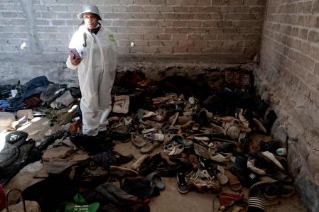 Una mujer registra ropa y zapatos encontrados en el Rancho Izaguirre, en la comunidad de La Estanzuela, donde el colectivo