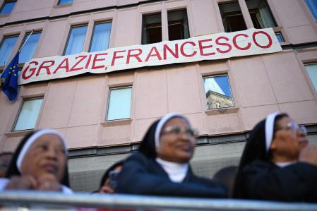 Monjas esperan bajo una pancarta que dice en italiano