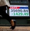 Peatones pasan junto a una pantalla que muestra el promedio de acciones del Nikkei en el exterior de una casa de bolsa en Tokio, Japón