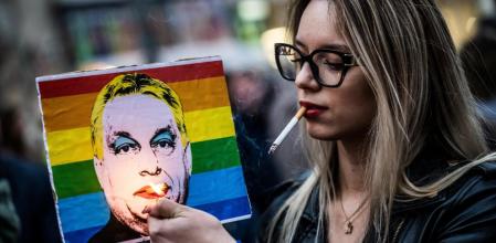 Una mujer enciende un cigarrillo en una imagen de Orbán durante una protesta en marzo por sus medidas contra la marcha del Orgullo