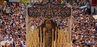 El paso de palio de la Virgen Nuestra Señora de la Hiniesta de la Hermandad del mismo nombre entre la multitud tras salir la Iglesia de San Julián de Sevilla