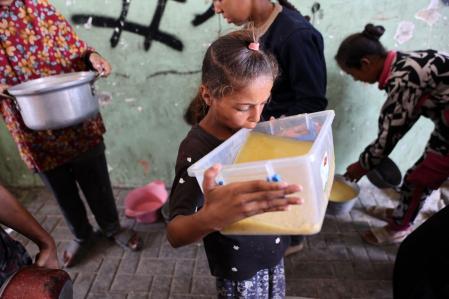 A displaced Palestinian girl takes a sip of lentil soup that she received at a food distribution point in Gaza City in the northern Gaza Strip on July 25, 2025. Aid groups warned of surging numbers of malnourished children in war-ravaged Gaza as a trio of European powers prepared to hold an