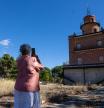 MADRID, 27/09/2024.- Una mujer fotografía una edificación en desuso durante la visita de la ministra de Vivienda, Isabel Rodríguez, al nuevo barrio de Campamento en Madrid este viernes, tras el desbloqueo esta semana de iniciativa urbanística de Campamento por el pleno del Ayuntamiento de Madrid. EFE/ Daniel González