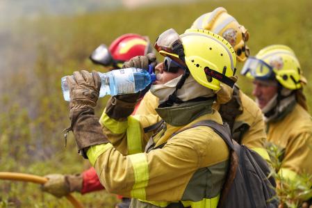 A firefighter takes a drink while working to extinguish a wildfire in Puercas de Aliste, near Zamora, on August 12, 2025. Dozens of blazes were reported in Spain over the last 24 hours including one that spread through Las Medulas, a UNESCO World Heritage site known for its ancient Roman gold mines. The wildfires coincide with what meteorologists expect to be the most intense day yet of the ongoing heatwave, with all regions under weather alerts. (Photo by CESAR MANSO / AFP)