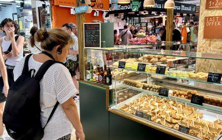 Una mujer con pignanillo observa las raciones de patatas bravas, calamares y croquetas.