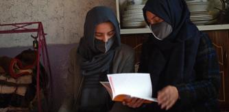 In this picture taken on December 23, 2022, Marwa (L), a student reads a book with her sister at their home in Kabul. Marwa was just a few months away from becoming the first woman in her Afghan family to go to university -- instead, she will watch achingly as her brother goes without her. Women are now banned from attending university in Taliban-controlled Afghanistan, where they have been steadily stripped of their freedoms over the past year.