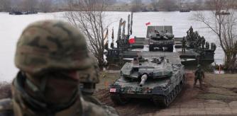 GNIEW, POLAND - MARCH 04: A Polish soldier stands by as Leopard 2PL main battle tanks of the Polish armed forces descend from M3 amphibious rigs of the German/British Amphibious Engineer Battalion 130 after crossing the Vistula River during the NATO Dragon 24 military exercise on March 04, 2024 near Gniew, Poland. Dragon 24 is involving 20,000 troops from 10 different nations and is part of Steadfast Defender 2024, an ongoing set of NATO military manoeuvres across Europe that is involving 90,000 troops. (Photo by Sean Gallup/Getty Images)