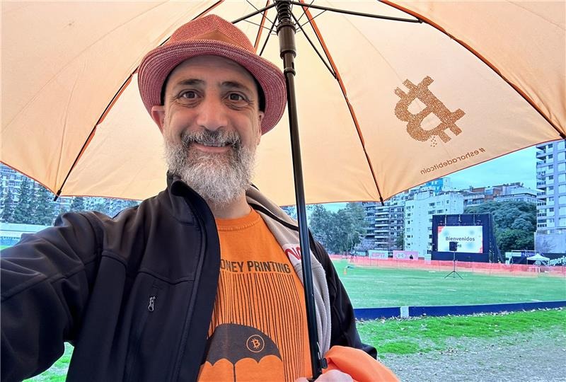 Rodolfo Andragnes, fundador de Bitcoin Argentina, con un paraguas que posee el logo de bitcoin.