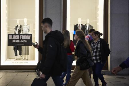 Varias personas pasan por delante de los comercios que anuncian los descuentos del Black Friday, a 23 de noviembre de 2022, en Madrid (España). Con la llegada del Black Friday, el 42% de los consumidores ha planificado anticipar sus compras navideñas, pero la inestabilidad de la situación económica y la incertidumbre está conduciendo también a muchos usuarios a esperar posibles ofertas de última hora, que serán 