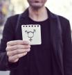 closeup of a young Caucasian man in the street showing a piece of paper with a transgender symbol drawn in it