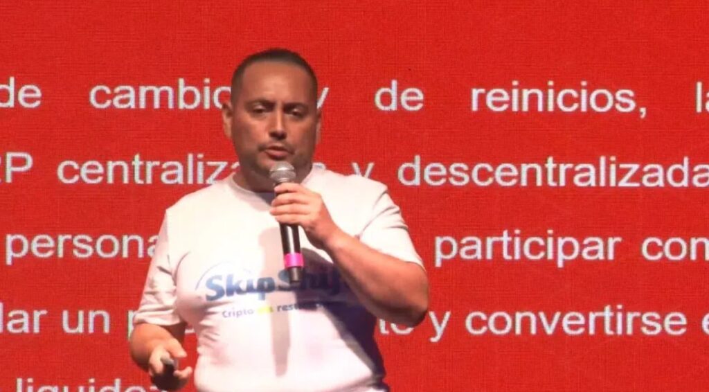 Fotografía del analista e inversor Daniel Andrés Peláez en un evento frente a un fondo rojo.