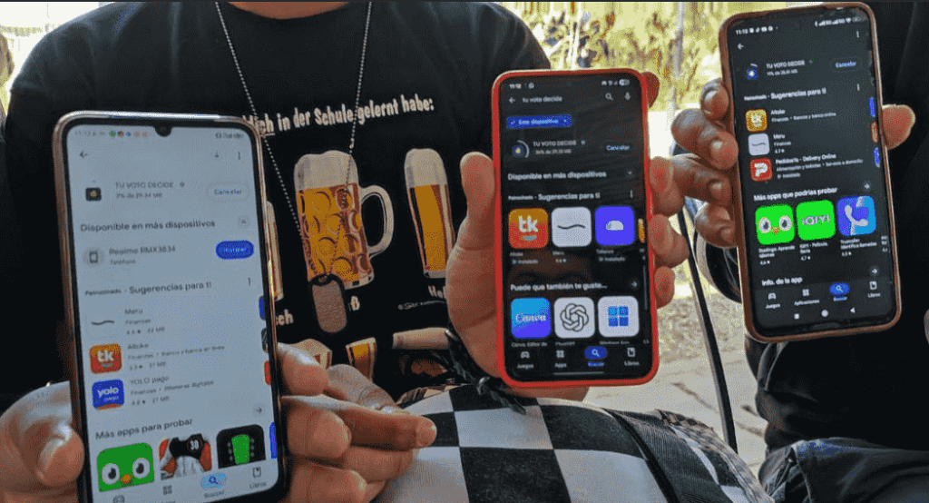 Primer plano de varios teléfonos móviles mostrados por personas que descargan la app Tu Voto Decide en Bolivia.