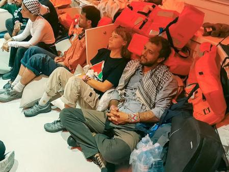 This handout picture released by the Israeli Foreign Ministry shows Swedish climate activist Greta Thunberg (C) and Brazilian activist Thiago Avila (R), along with other activists, after the Israeli navy intercepted the Global Sumud Flotilla carrying humanitarian aid to Gaza on October 1, 2025, as stated by the ministry. Israel said on October 2 it will deport to Europe pro-Palestinian activists on an aid flotilla headed towards Gaza as the Israeli navy intercepted vessel after vessel in the Mediterranean. The Global Sumud Flotilla of around 45 vessels began its voyage to Gaza last month, with politicians and activists including Thunberg aiming to break Israel's siege of the Palestinian territory, where the United Nations says famine has set in. (Photo by Israeli Foreign Ministry / AFP)