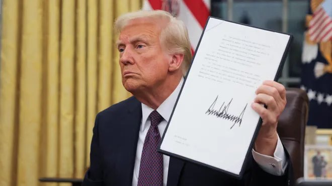 Foto de Donald Trump sosteniendo en sus manos una orden ejecutiva firmada por él