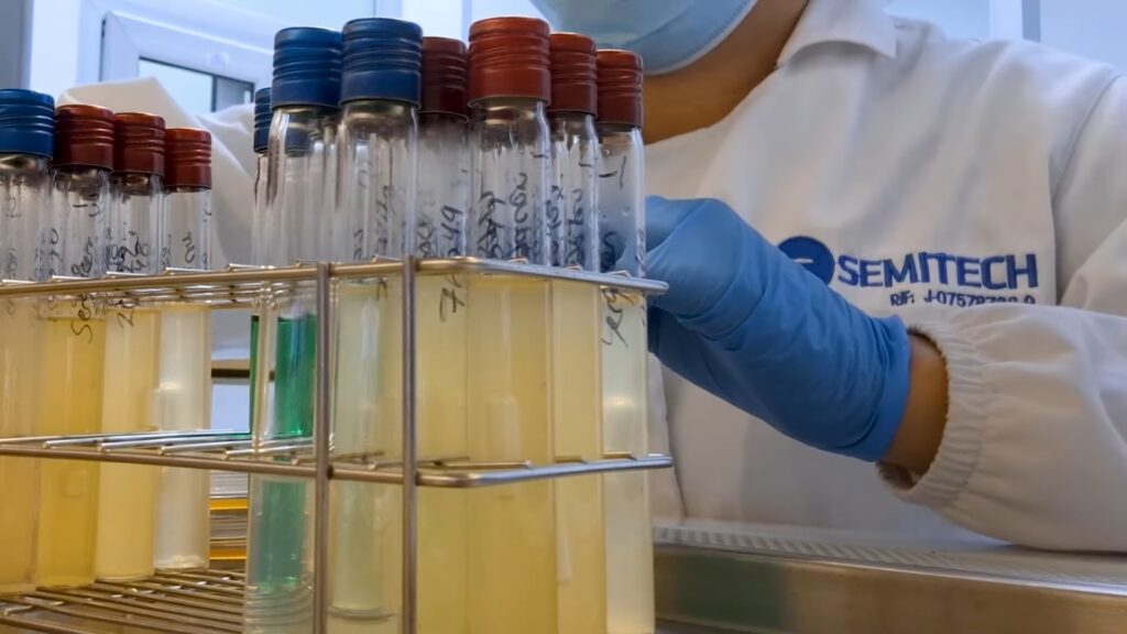 Fotografía de una analista de laboratorio de SEMITECH con tubos de ensayo y líquidos.
