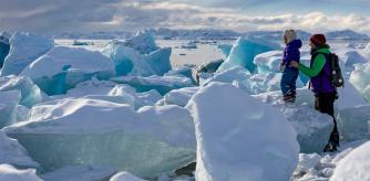 TOPSHOT - A family plays among beached icebergs in Nuuk, Greenland, on March 4, 2025. US President Donald Trump has strained relations with Denmark by repeatedly signalling that he wants control over Greenland, an autonomous Danish territory which will hold legislative elections on March 11. (Photo by Odd ANDERSEN / AFP)