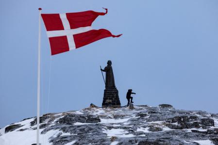 FILE PHOTO: A man walks as Danish flag flutters next to Hans Egede Statue ahead of a March 11 general election in Nuuk, Greenland, March 9, 2025. REUTERS/Marko Djurica/File Photo