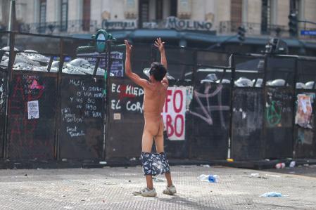 Un manifestante, con los calzones bajados frente a la línea policial.
