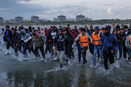 Un grupo de migrantes corre hacia el mar tratanddo de llegar a embarcaciones ilegales que cruzan el Canal.&nbsp;