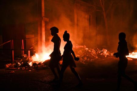 Jóvenes cubanos pasan por delante de una hoguera encendida durante las protestas del jueves en el barrio Lawton de La Habana.